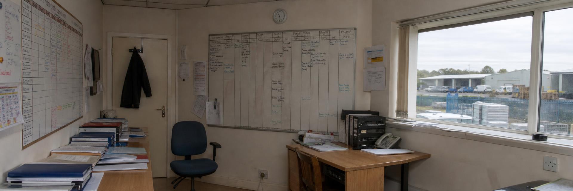 A job planner board and schedule folders in a small operations office