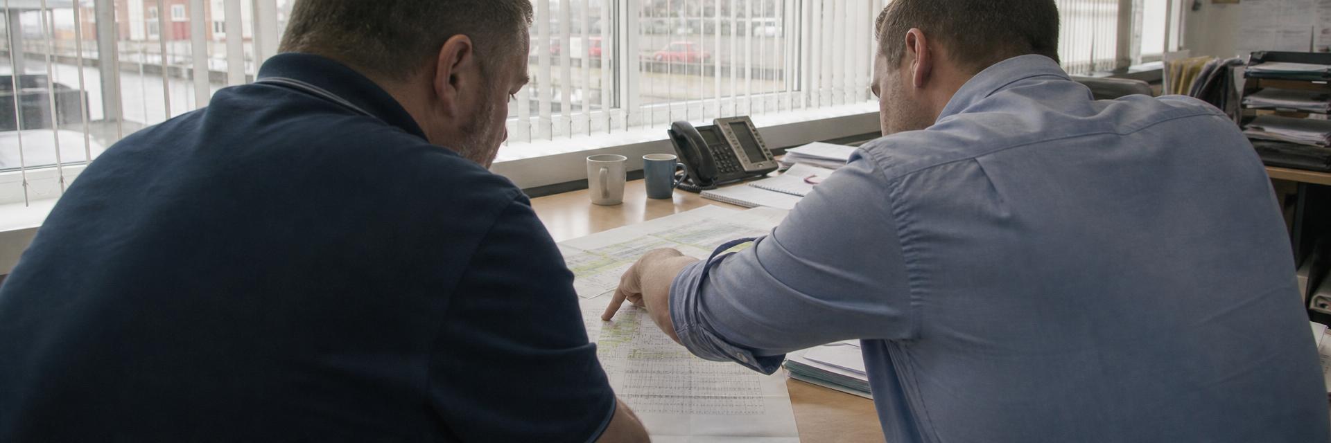 An owner and colleague reviewing job schedules and figures at a desk